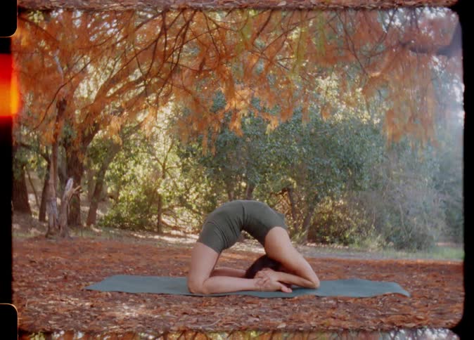 A woman doing a yoga pose in a forested area in autumn