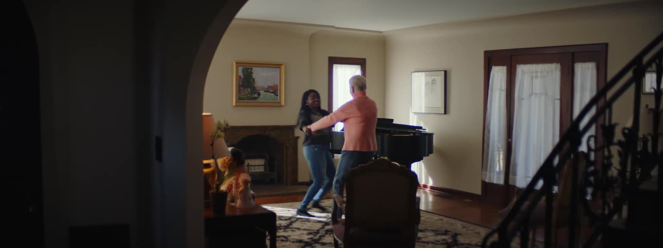 Two women holding hands and spinning in a circle in a living room