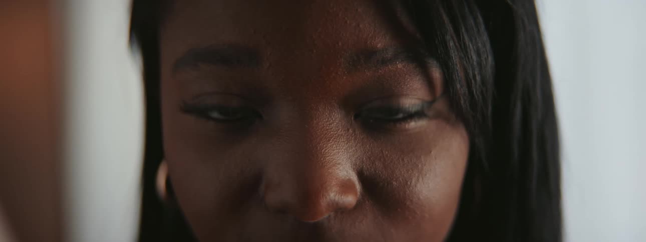 Woman with black hair and earrings smiles at camera in room
