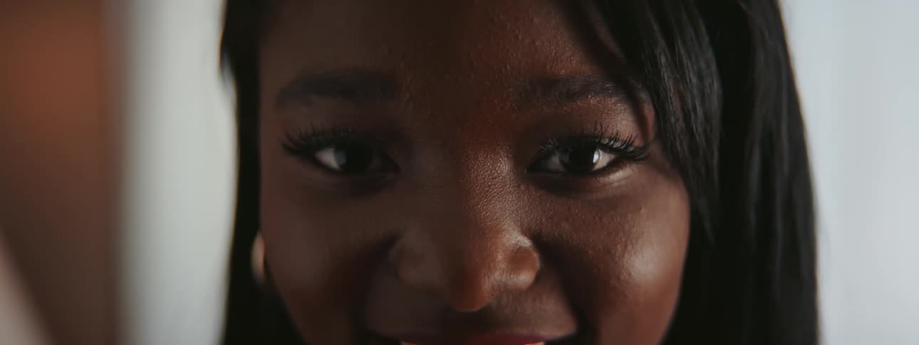 Woman with black hair and earrings laughs at camera