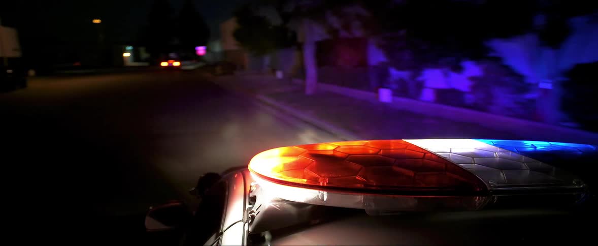 Police car with emergency lights activated chases car in the street at night
