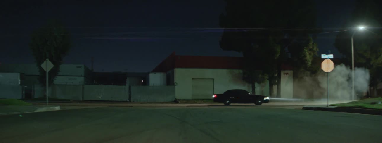 Black car driving on street escapes police car at night