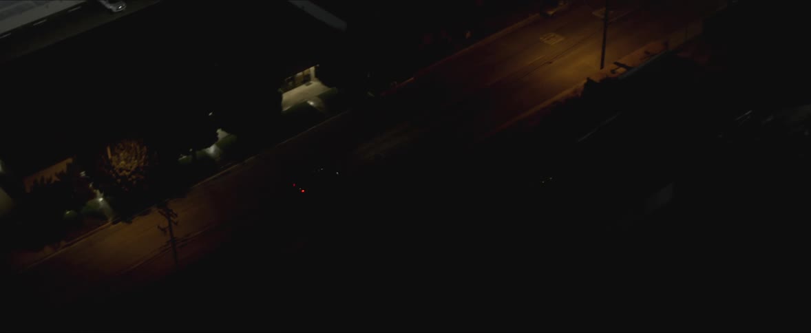 Aerial view of black sports car escapes police car in the city at night