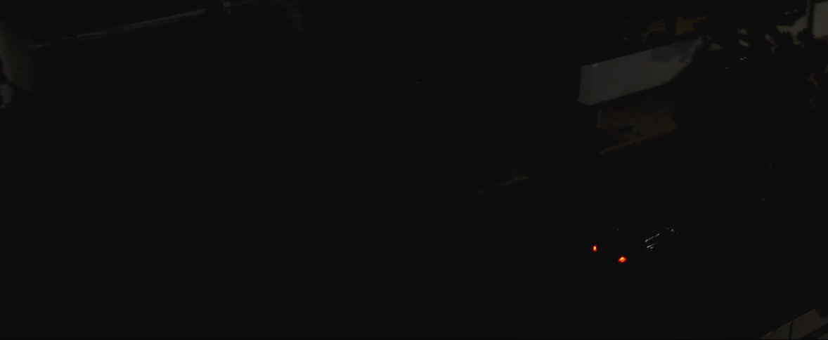 Aerial view of black car being chased after by police car in the neighborhood at night