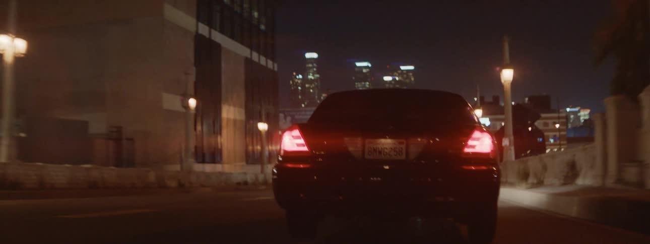 Black car escapes police car in the city streets at night