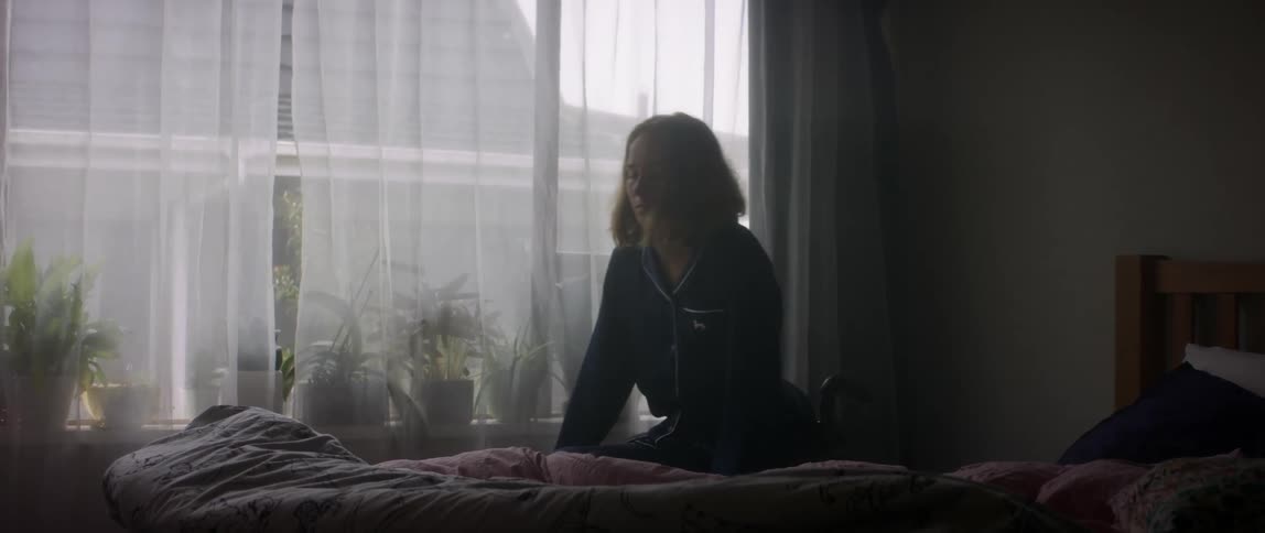 A disabled woman pulls herself out of bed and into the wheelchair then starts rolling out of the bedroom