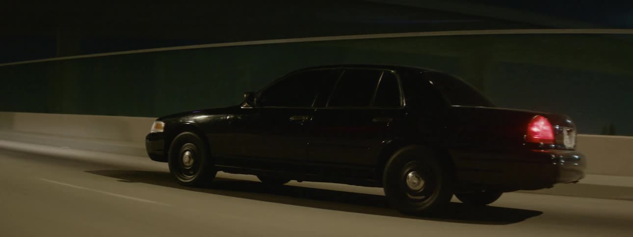A black car driving down a highway at night