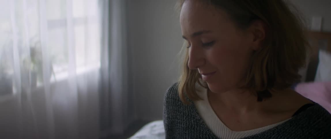 Young woman sitting on the bed at home talks to a baby