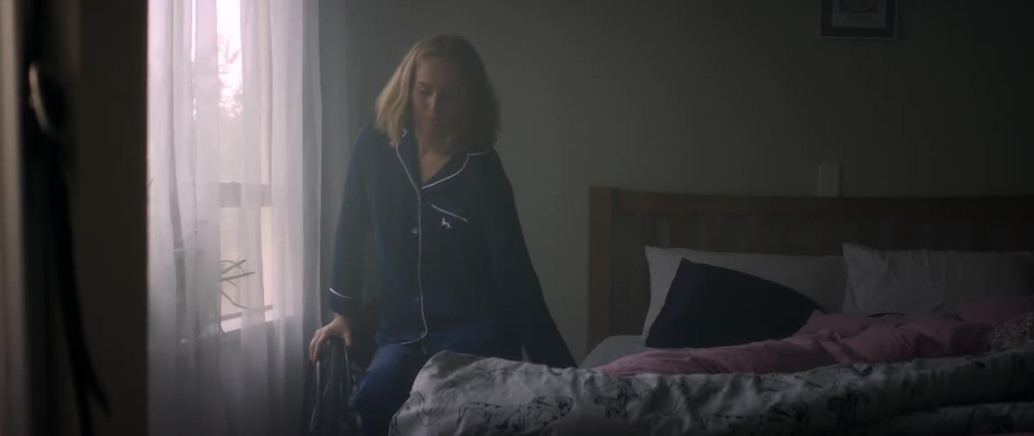 A women stretching on the side of her bed and then moving herself to her wheelchair