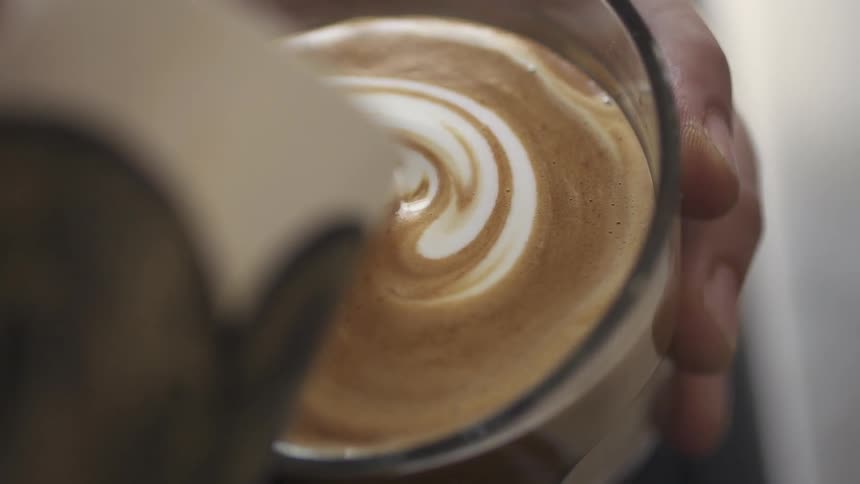 A barista pouring cream into espresso