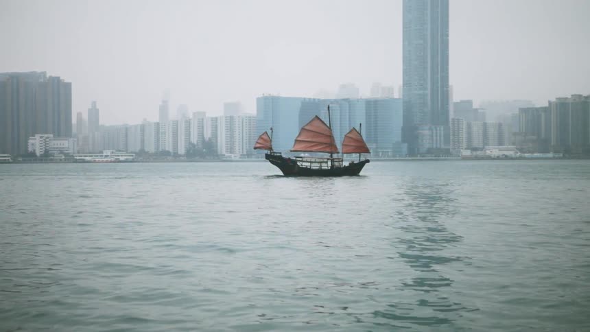 A sailboat navigates Hong Kong Harbor
