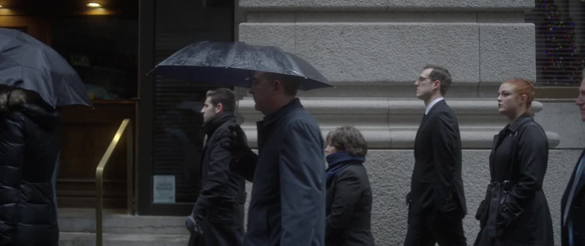 People walk down a city street in the rain