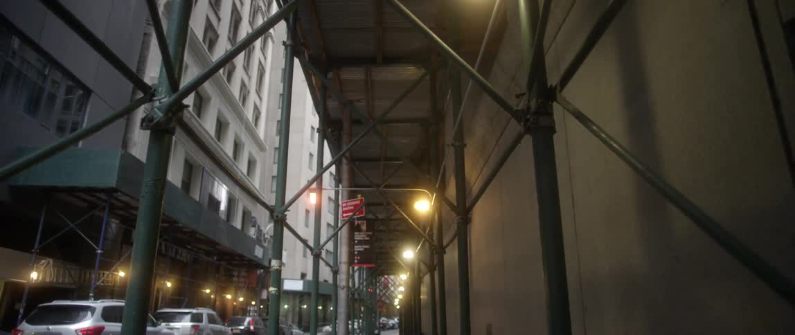 Lights shining under scaffolding set up next to a building