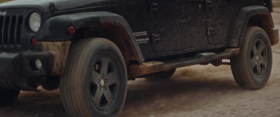 A black jeep is turning on a dirt road in the desert