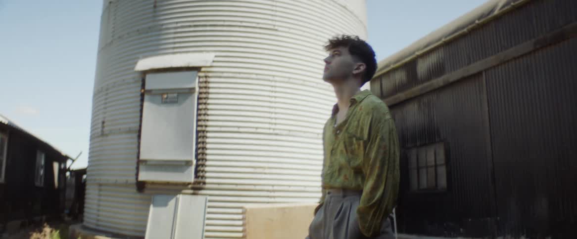 Young standing near a silo close to a barn on a farm at daytime