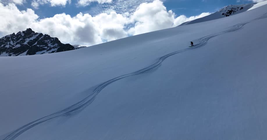 A person skis down a snowy mountain next to tracks