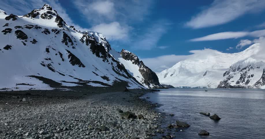 A view of a lake a the base of mountains covered in snow