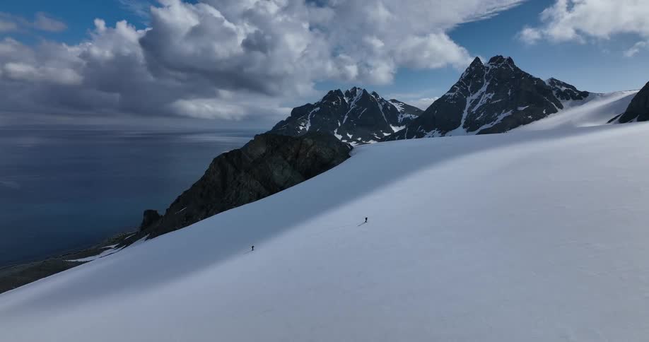 Aerial view of distant two men going up snowy mountain