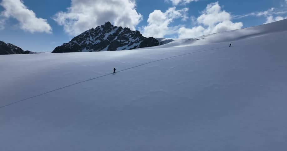 Two people are hiking up a mountain in winter