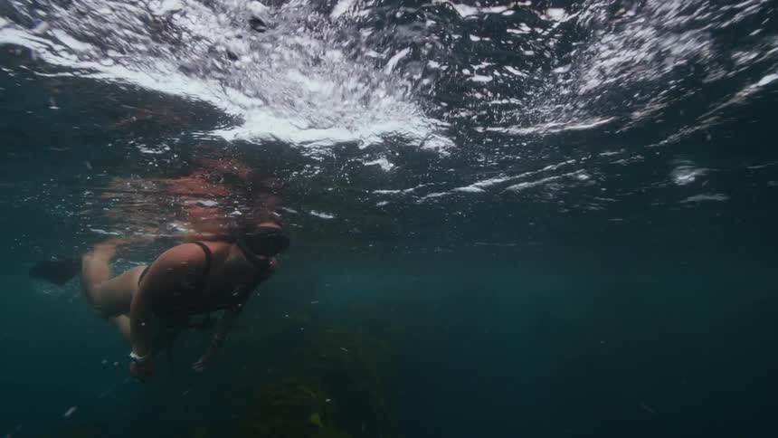 A woman snorkeling and swimming near the surface