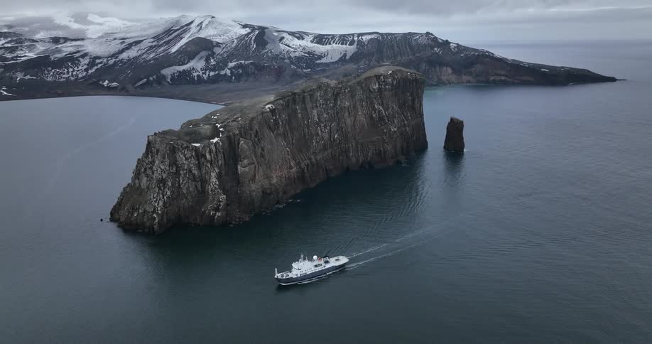 Shot of a expedition ship sailing next to a rock into sunken crater