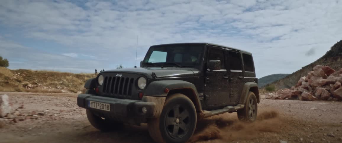 A jeep drives on a dirt road in a hilly area