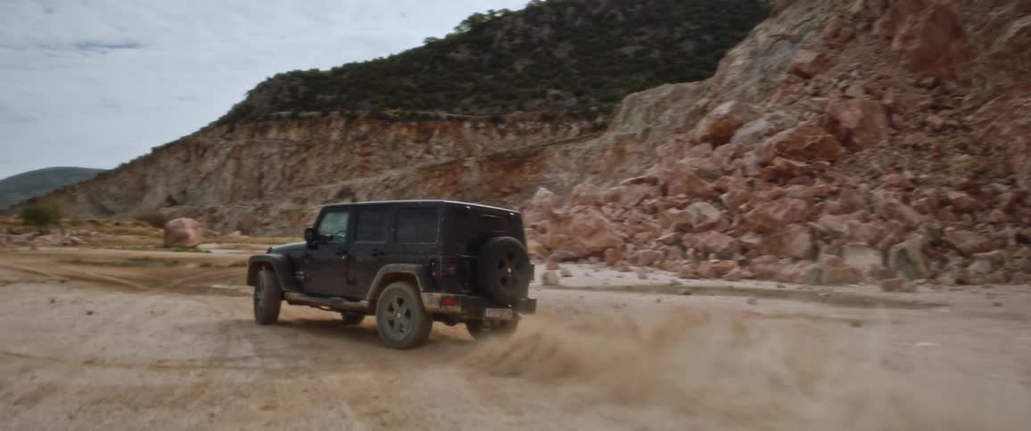 A jeep drives off road past a cliff