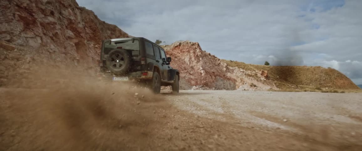 A black jeep drifting and spinning out on a desert rocky road with rocky mountains