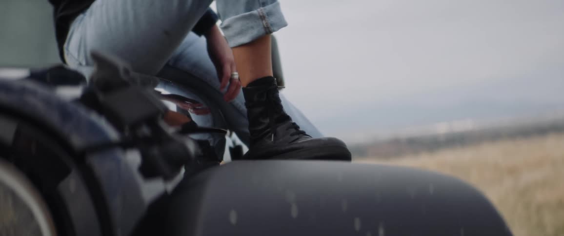 A closeup of a person sitting on the hood of their jeep