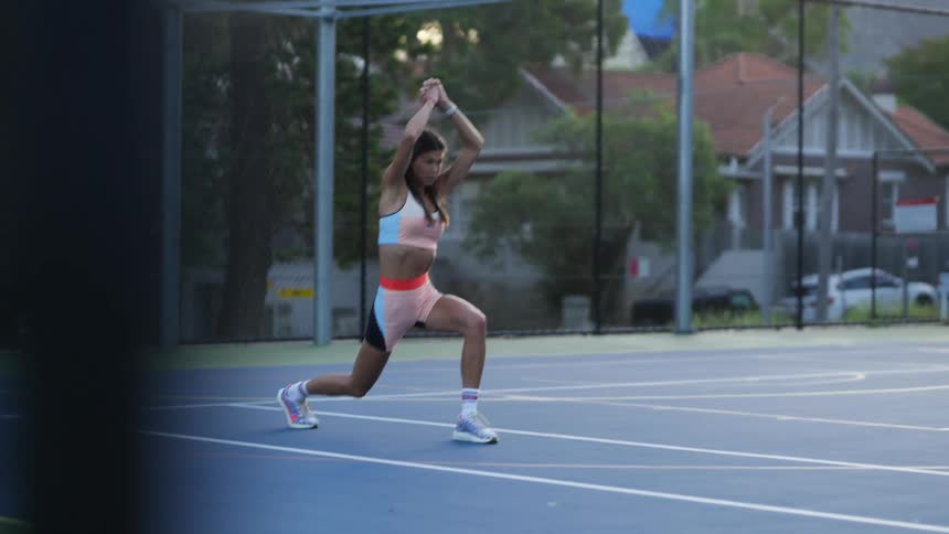 Woman in athletic gear stretching on the neighborhood basketball court