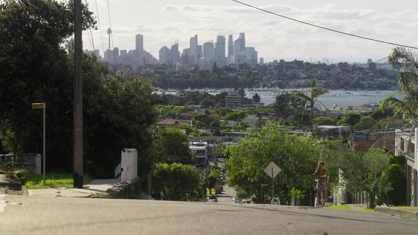 Woman running up the hill in the suburbs the downtown skyline and a bay can be seen in the background