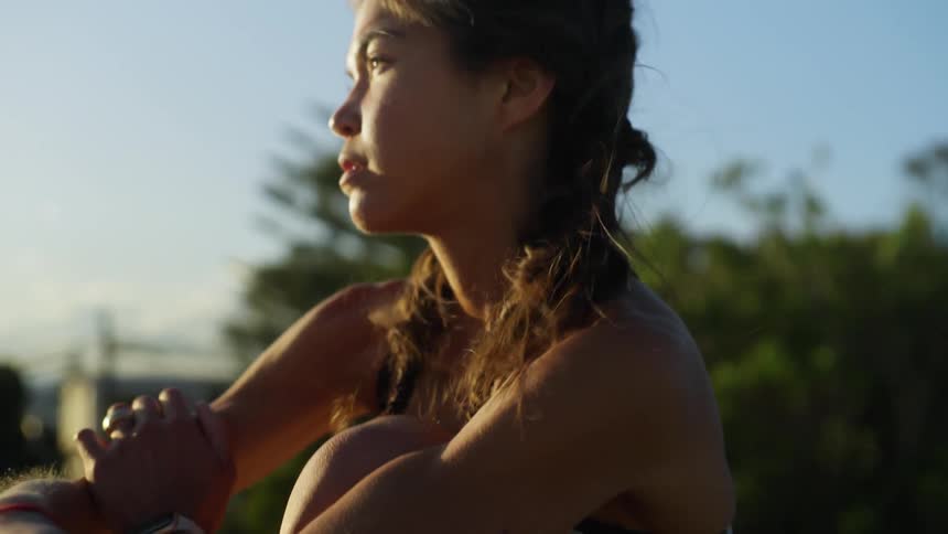 Woman wearing a crop top and shorts crosses her arms while overlooking the view on a sunlit day with a slight breeze