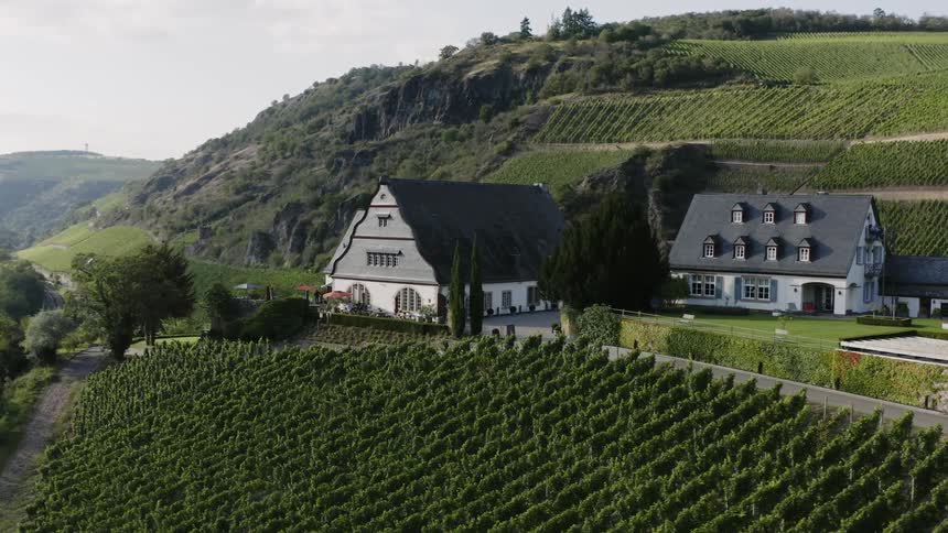 A single family home and a barn sit at the base of a hill on a farm