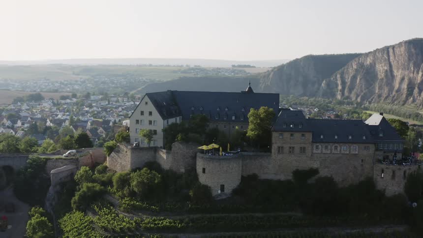 A large castle like structure sits atop a hill over a neighborhood