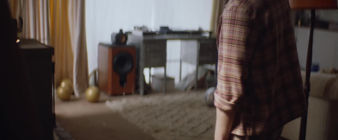 A teenage boy is looking at himself in the mirror and fixing his shirt