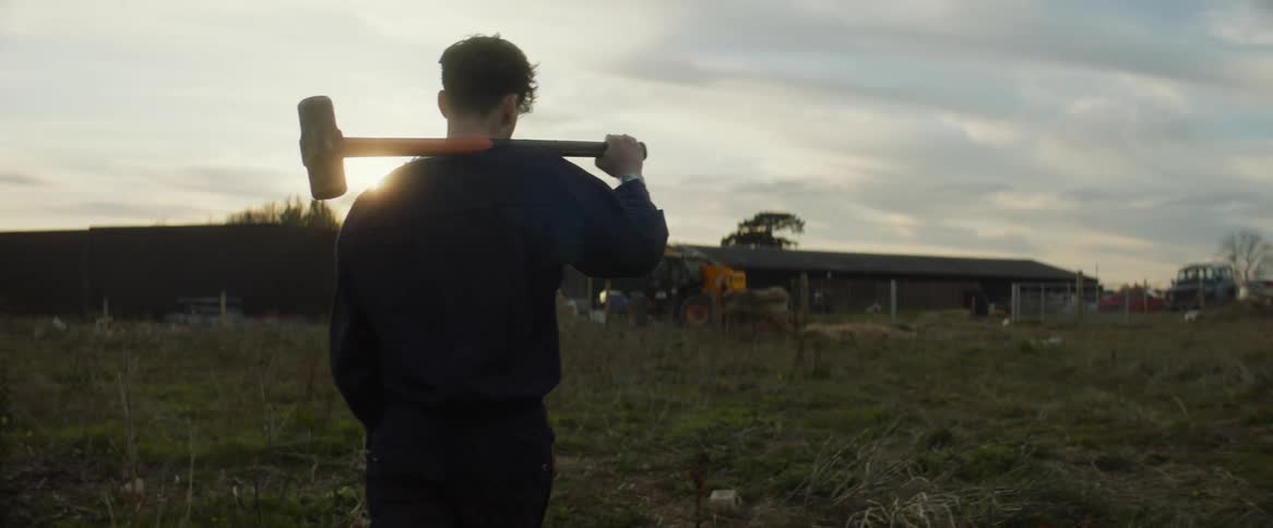 A man carries a sledgehammer towards the home