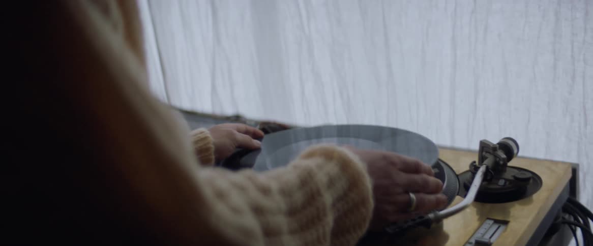 A teenage boy at home puts a record on a turn table