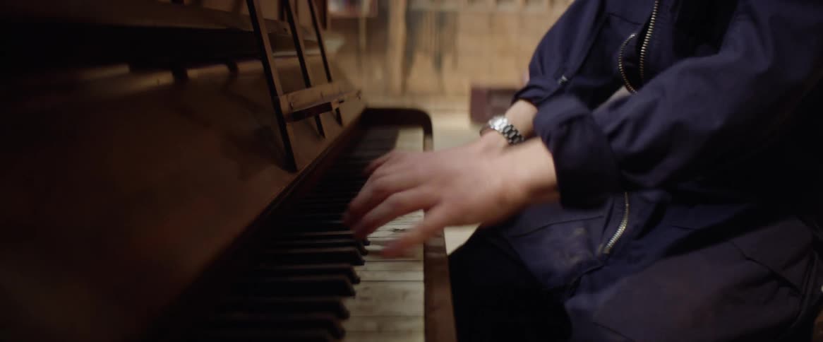 Man in a black shirt plays piano indoors