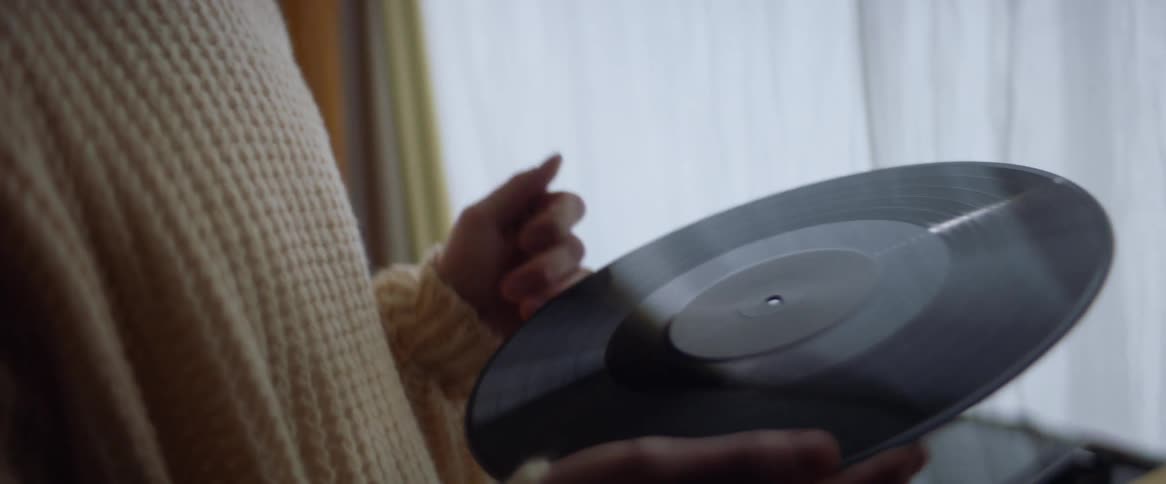 A teenage boy is standing indoors and holding a record