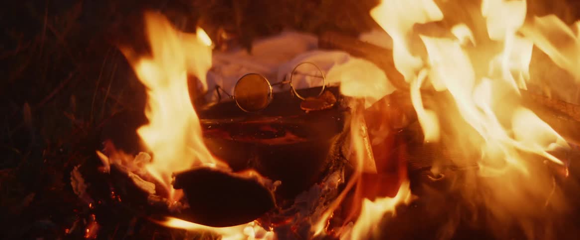 A camp fire burning outdoors at night