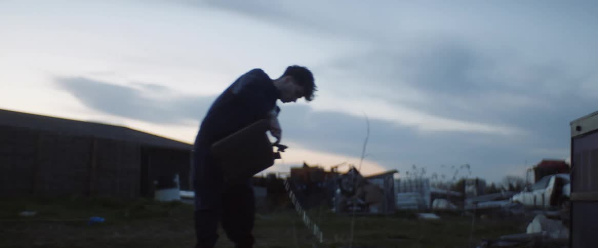 A man pours gasoline on a pile of trash