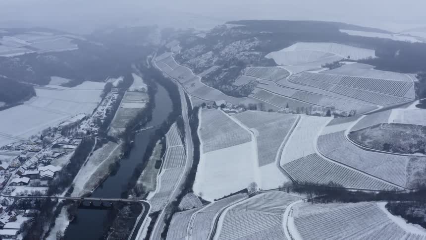 Snow covers rows of crops in the countryside