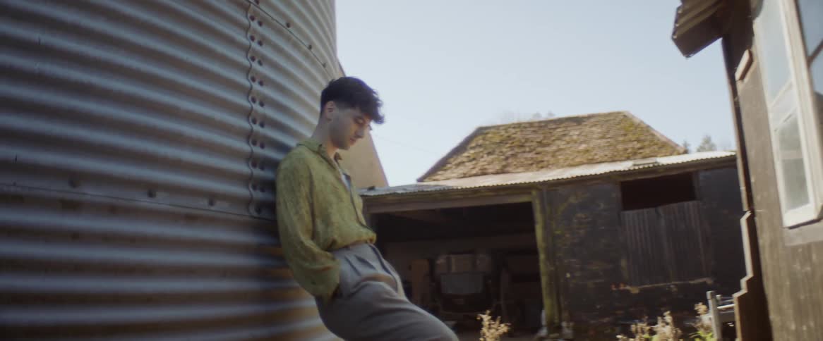 Man leans against corrugated metal structure outdoors