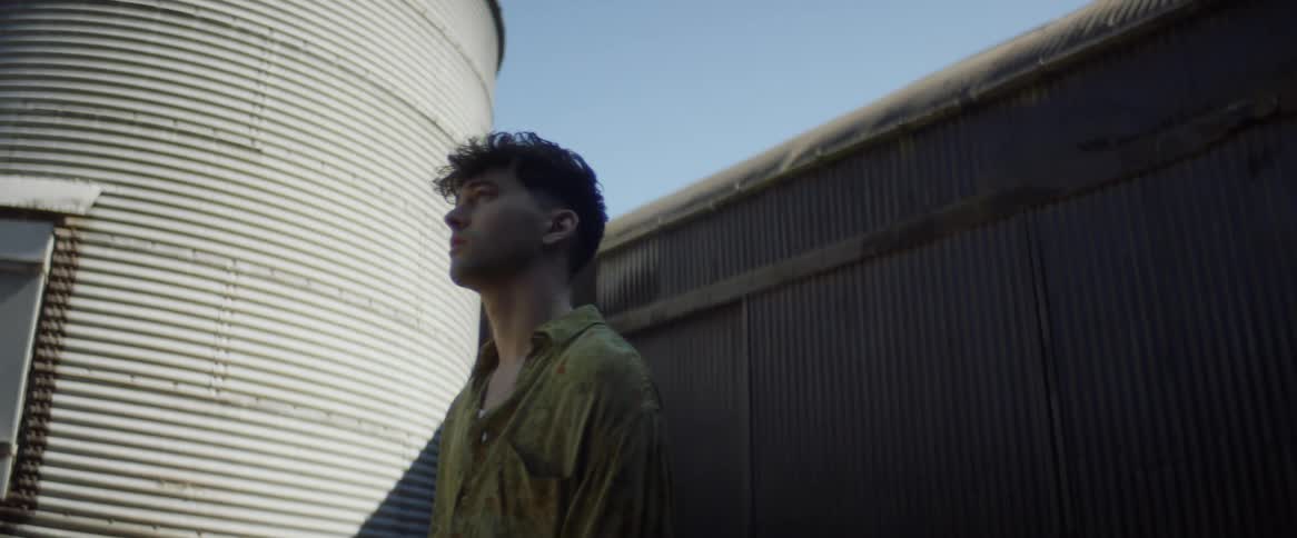 A man stands next to a grain silo
