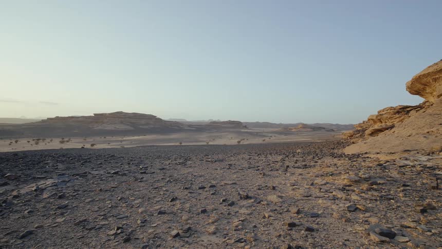 A wide shot of a desert landscape covered in dirt sand and rocks in Saudi Arabia