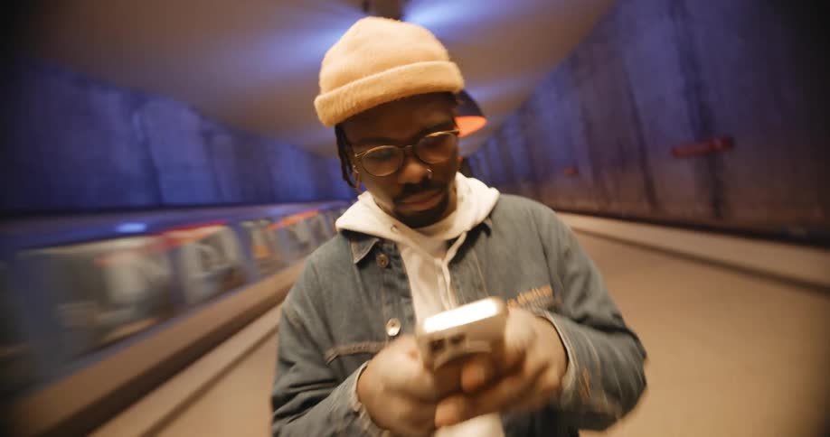 A man texts on his phone as a passenger train passses underground