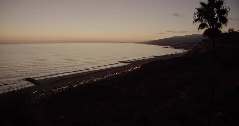 Traffic flows slowly in one direction and quickly in the opposite direction on beachside highway at night