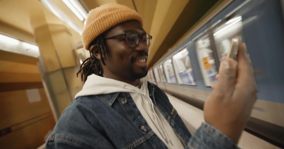 A man pulls his phone out of his pocket while waiting at a train station