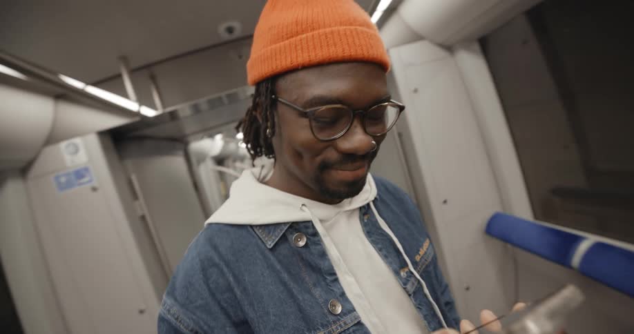 A man lifts up his cell phone and looks at it and smiles