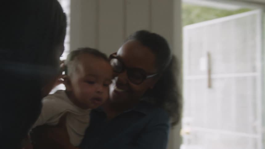 A man smiles wide after handing his baby to his wife